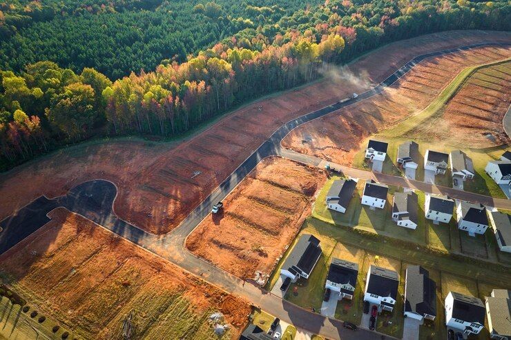 Aerial view of a housing development under construction with nearby forest and completed homes.